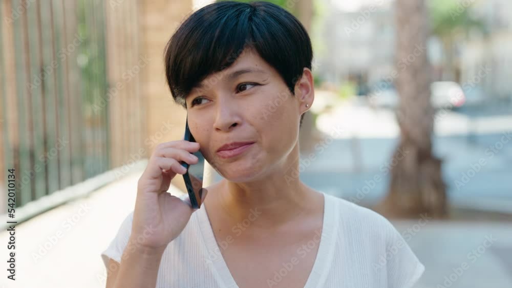 Middle age chinese woman smiling confident talking on the smartphone at street Middle age chinese woman smiling confident talking on the smartphone at street