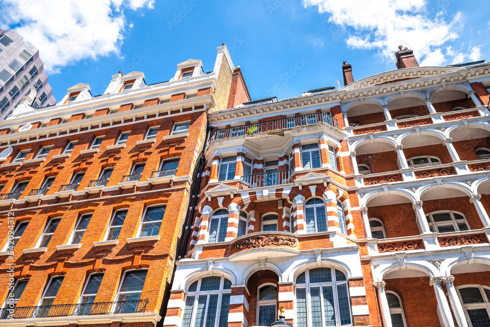 Fototapeta premium Looking up low angle view on apartment flats house building in Gothic revival style architecture in city of Westminster, London UK with blue sunny sky