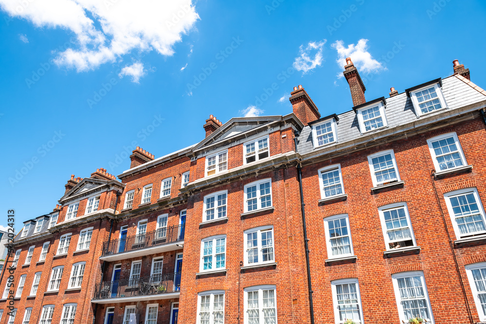 Fototapeta premium Apartment flats house building in Gothic revival style architecture in city of Westminster, London UK with blue summer sunny sky