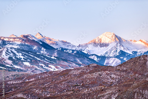 Aspen, Colorado Mt Daly peak in sunlight in Rocky Mountains winter snow slope at colorful pastel blue and purple morning sunrise