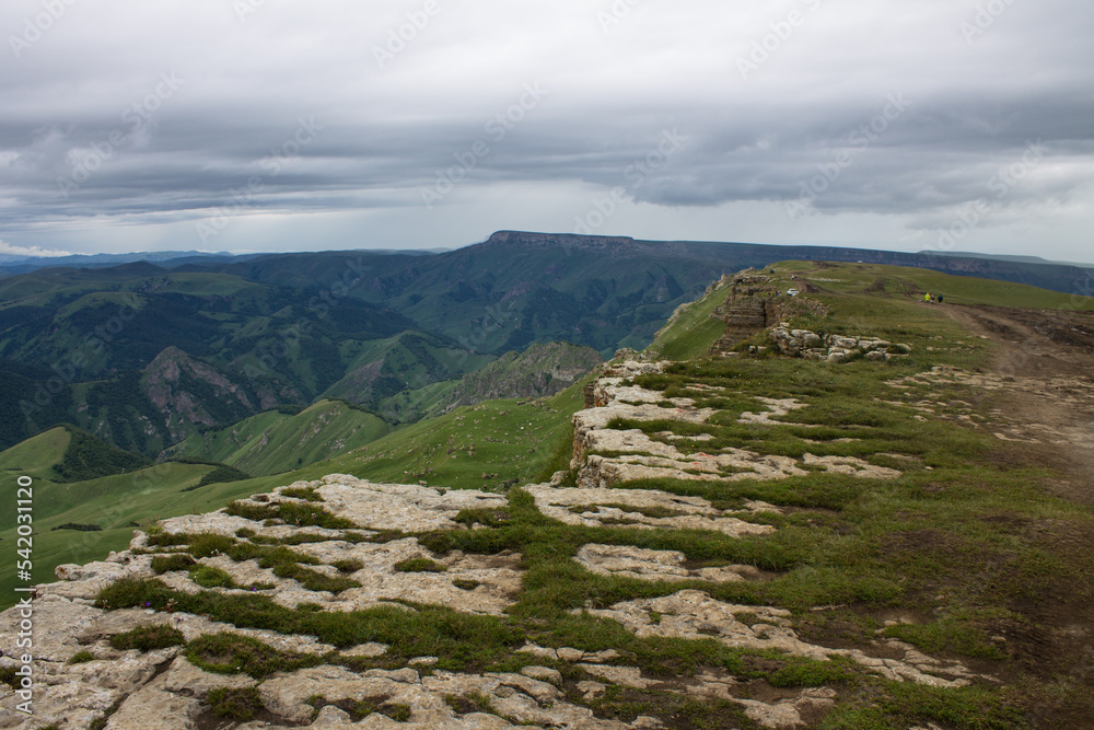 Dramatic landscape - panoramic view of the hilly valley from the Bermamyt plateau in Karachay-Cherkessia in a misty haze and stone cliffs Dramatic landscape - panoramic view of the hilly valley from the Bermamyt plateau in Karachay-Cherkessia in a misty haze and stone cliffs