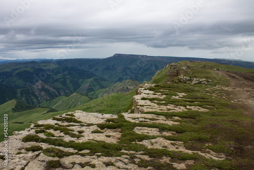 Dramatic landscape - panoramic view of the hilly valley from the Bermamyt plateau in Karachay-Cherkessia in a misty haze and stone cliffs © Inna