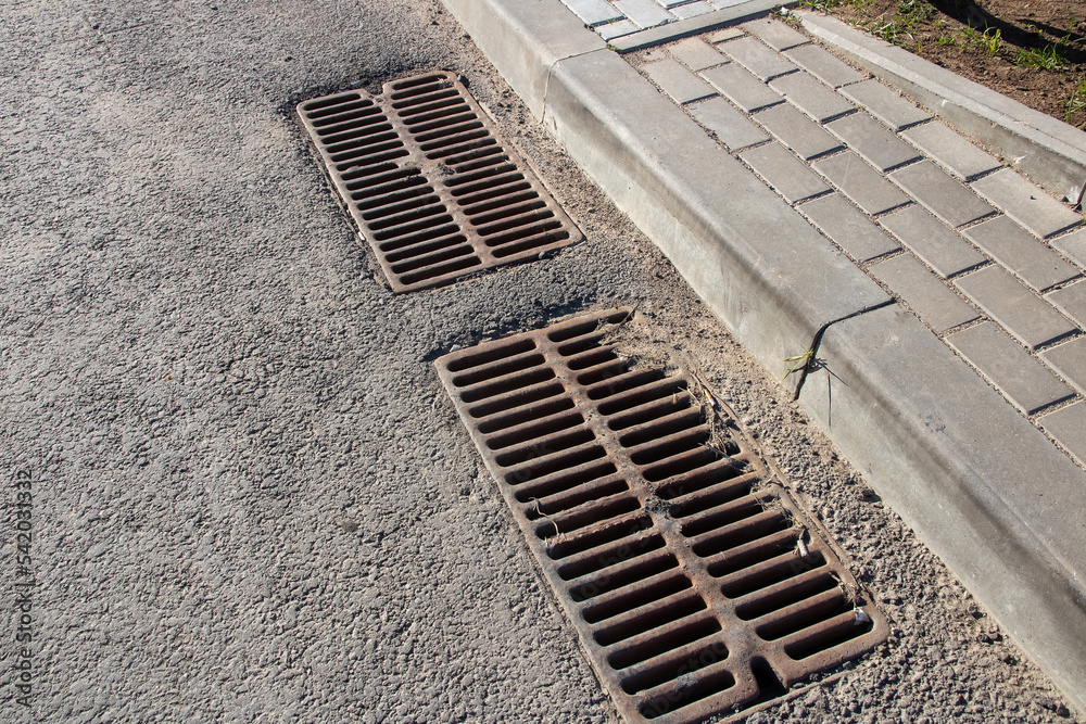 Obraz premium Long sewer grate on gray asphalt closeup