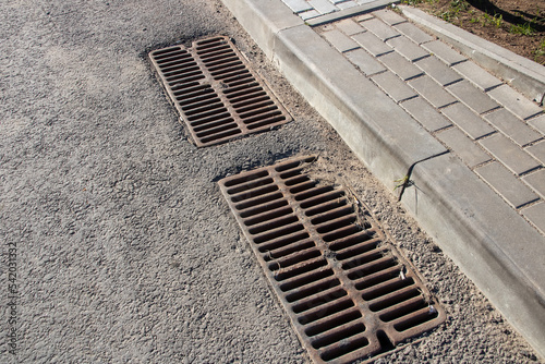 Long sewer grate on gray asphalt closeup