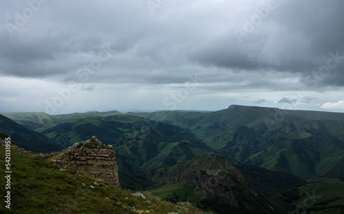 Panoramic view of green mountains and hills from the Bermamyt plateau in Karachay-Cherkessia in Russia on a cloudy summer day and copy space in a hazy haze on the horizon