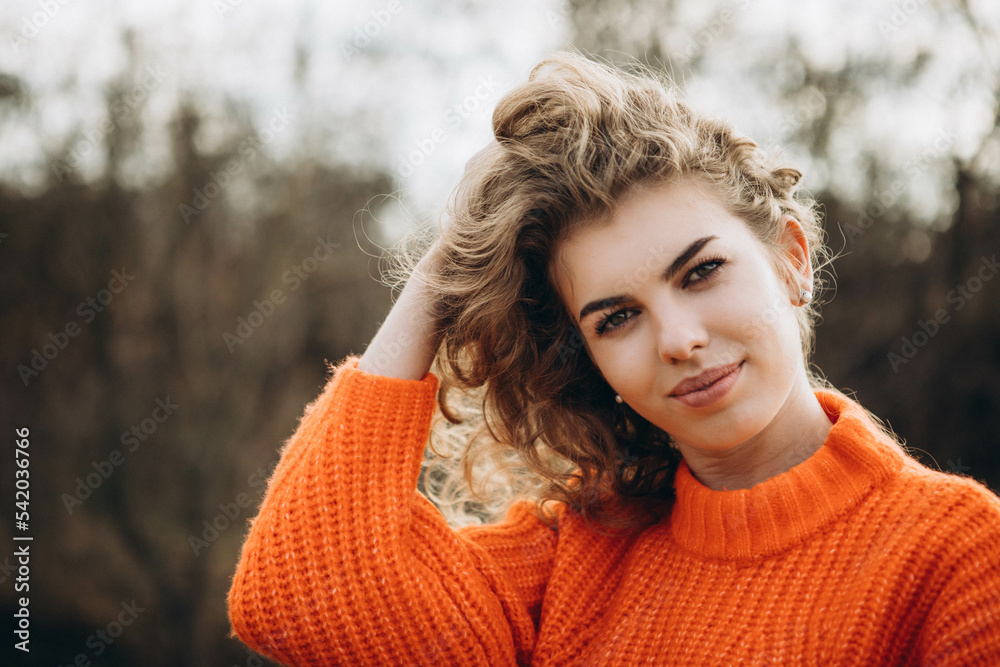 young curly girl in an orange sweater against the backdrop of autumn nature young curly girl in an orange sweater against the backdrop of autumn nature