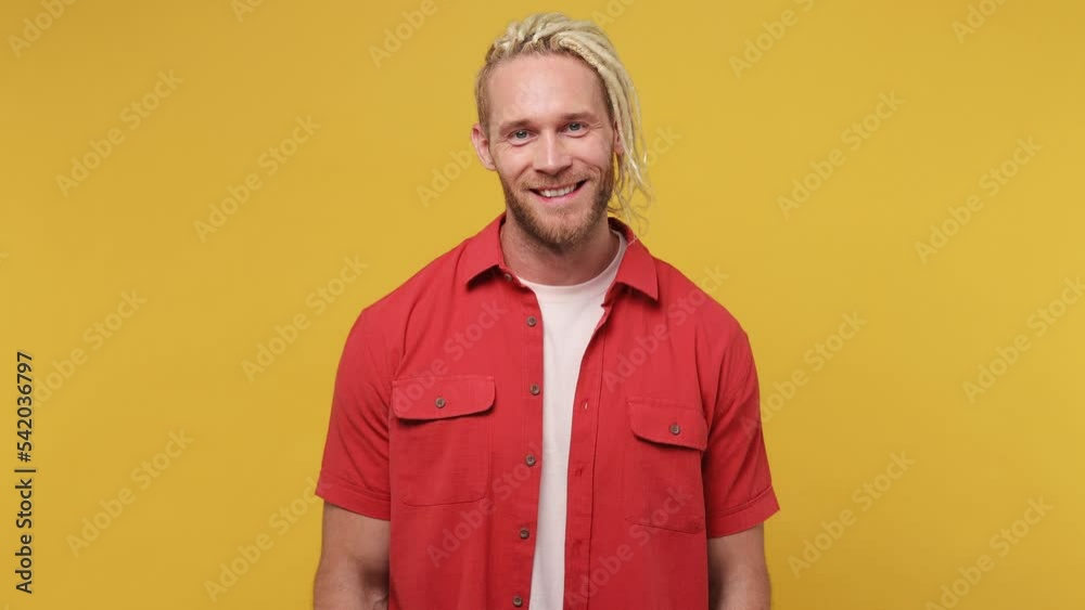Young blond man with dreadlocks 30s he wear red shirt white t-shirt look around think dream put hand prop up on chin lost in thought and conjectures isolated on plain yellow background studio portrait Young blond man with dreadlocks 30s he wear red shirt white t-shirt look around think dream put hand prop up on chin lost in thought and conjectures isolated on plain yellow background studio portrait