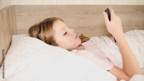child lying in bed playing mobile phone. photo