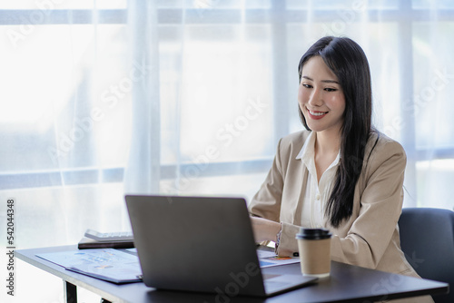Asian businesswoman working in finance and calculator working with laptop computer with paper documents at office Technology market and financial concepts