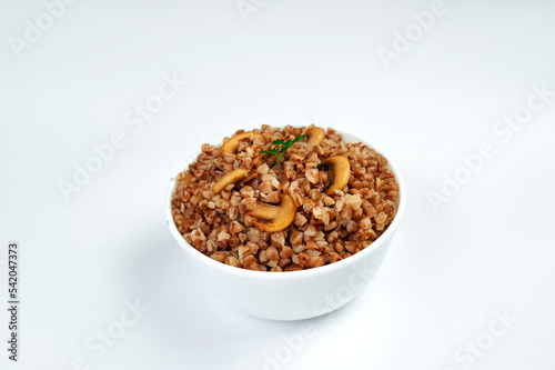 buckwheat porridge in a white plate with mushrooms on a plate, white background © Denys