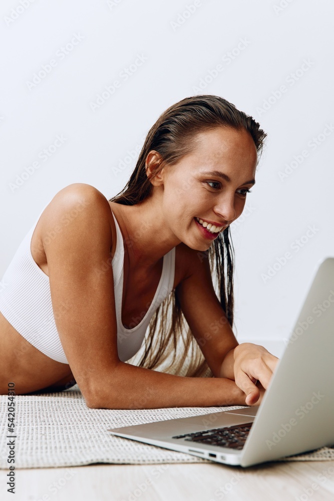 A woman lies on the floor at home and smiles with her teeth while looking at a laptop while chatting online and watching TV shows on her day off A woman lies on the floor at home and smiles with her teeth while looking at a laptop while chatting online and watching TV shows on her day off