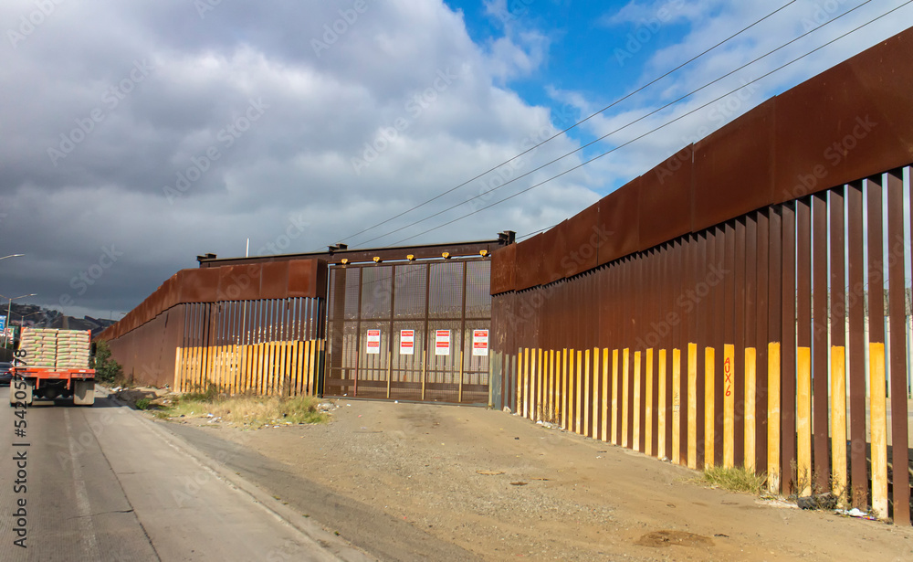 View of border wall with as seen driving on road with truck in the distance View of border wall with as seen driving on road with truck in the distance