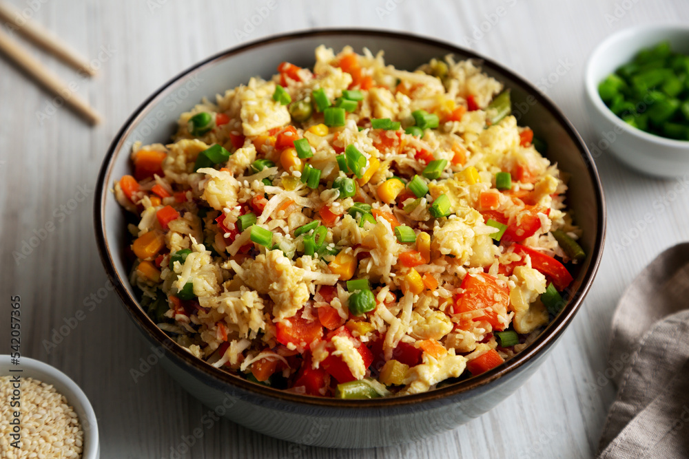 Homemade Cauliflower Fried Rice with Chives and Sesame Seeds in a Bowl, side view. Close-up. Homemade Cauliflower Fried Rice with Chives and Sesame Seeds in a Bowl, side view. Close-up.