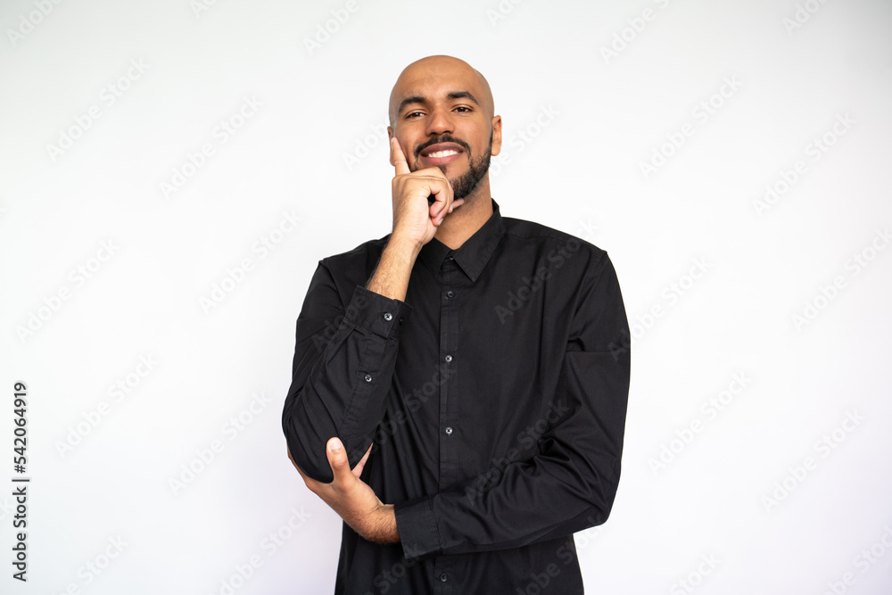 Portrait of attentive young man leaning on hand. Happy Latin American male model with bald head and beard in black shirt looking at camera, smiling. Contemplation, focus concept Portrait of attentive young man leaning on hand. Happy Latin American male model with bald head and beard in black shirt looking at camera, smiling. Contemplation, focus concept
