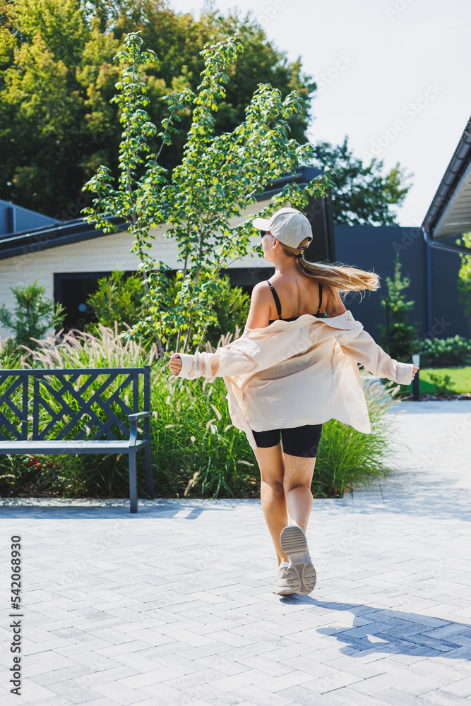 Slim young stylish woman in a black top and shorts, wearing an oversized jacket. A stylish girl walks down the street. stylish summer fashion outfit. sunglasses,
