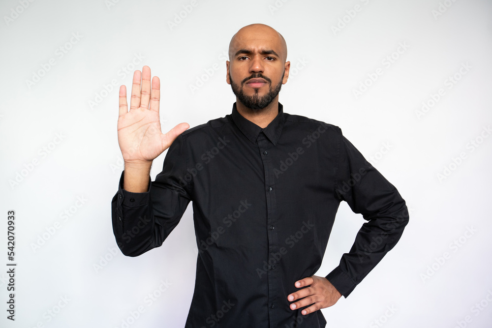 Portrait of upset young man showing stop sign. Strict multiethnic male model with bald head and beard in black shirt looking at camera with open palm. Warning or restriction concept Portrait of upset young man showing stop sign. Strict multiethnic male model with bald head and beard in black shirt looking at camera with open palm. Warning or restriction concept