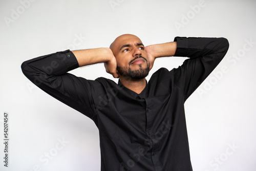 Fotografie Portrait of confident young man covering ears and looking away against white background