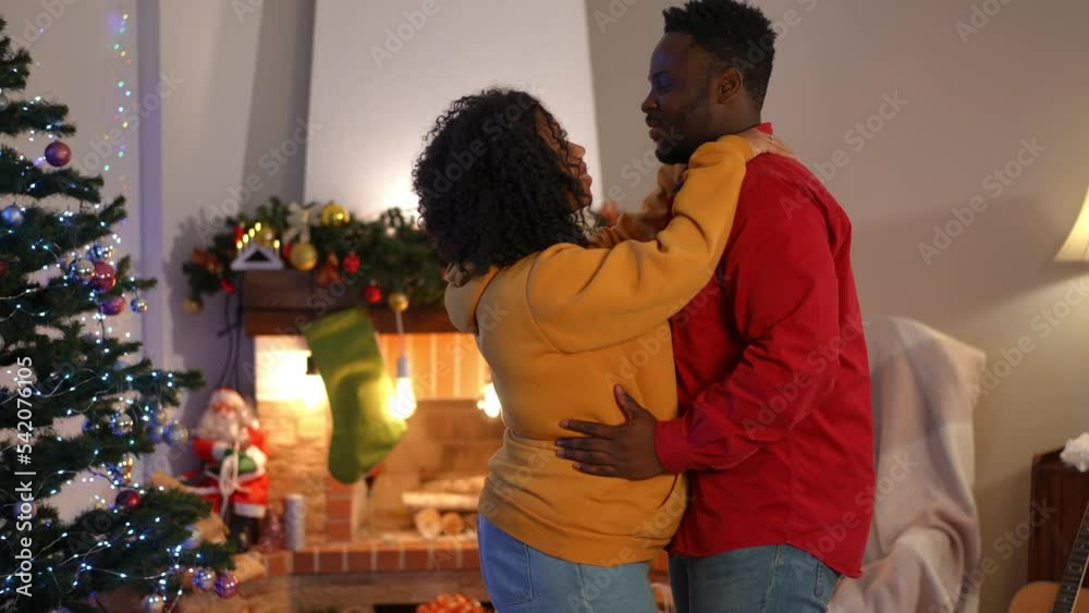 Side view loving couple rubbing noses talking dancing on Christmas in living room at home. Loving romantic African American husband and wife celebrating New Year's eve together enjoying leisure Side view loving couple rubbing noses talking dancing on Christmas in living room at home. Loving romantic African American husband and wife celebrating New Year's eve together enjoying leisure