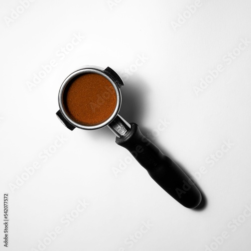 Closeup of a portafilter full of coffee isolated on white background photo