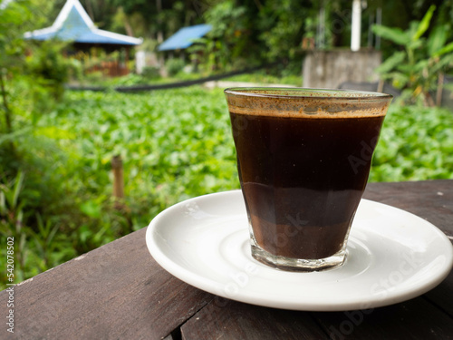 A cup of black coffee on a white ceramic plate