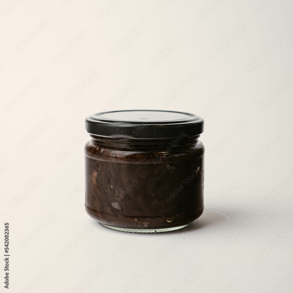 Transparent jar with a black lid containing food on a neutral background Transparent jar with a black lid containing food on a neutral background