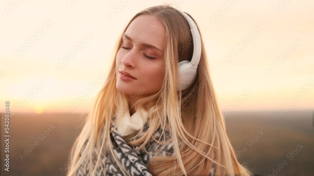 Relaxed young woman with long flying hair in headphones listening to music and dancing on the top of mountains with incredible sunset on the background. Inspiration time. Relaxed young woman with long flying hair in headphones listening to music and dancing on the top of mountains with incredible sunset on the background. Inspiration time.
