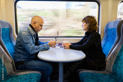Adult couple sitting near a train window having coffee