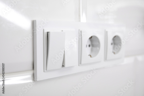 Light switch and power sockets on white wall indoors  closeup