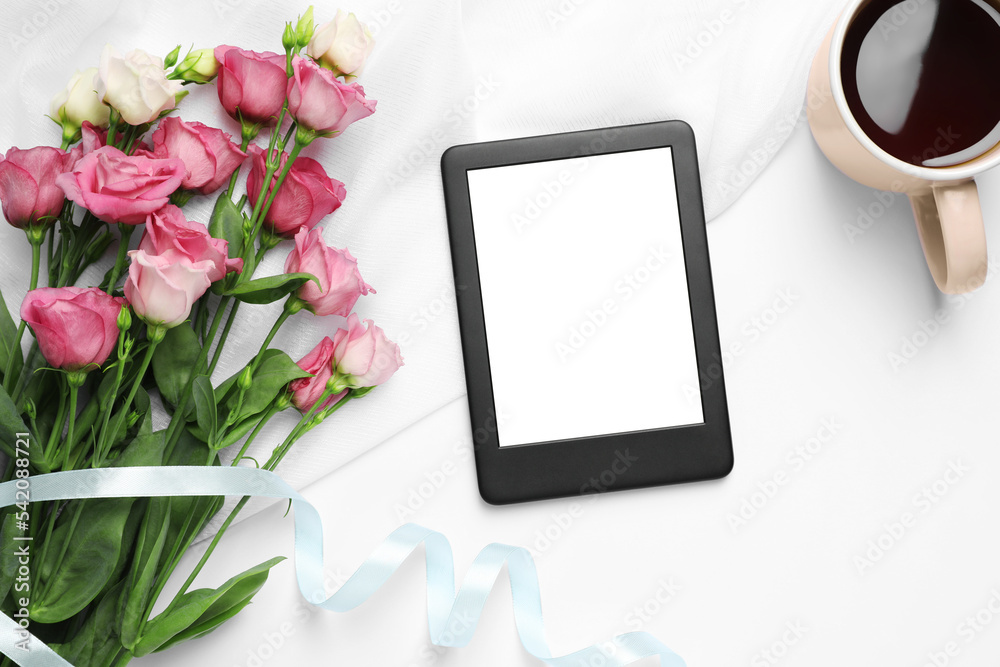 Modern e-book reader, flowers and cup of tea on white table, flat lay Modern e-book reader, flowers and cup of tea on white table, flat lay
