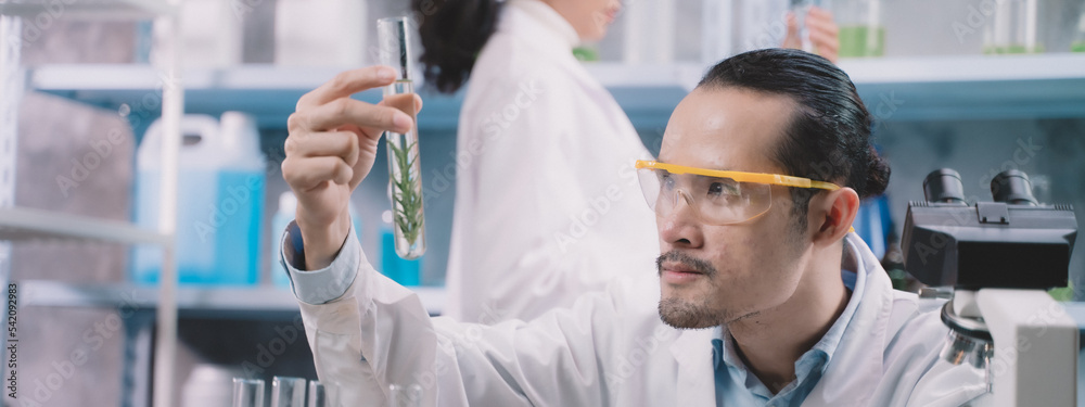 Researcher men are looking to simple reefs in tube on his hands and research women are hold a simple tube on behind researcher men at cosmetic lab and laboratory Researcher men are looking to simple reefs in tube on his hands and research women are hold a simple tube on behind researcher men at cosmetic lab and laboratory