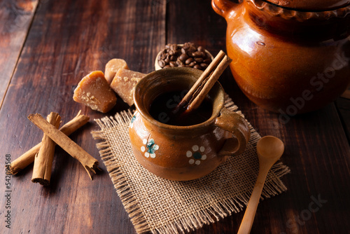 Authentic homemade mexican coffee (cafe de olla) served in traditional handmade clay mug (Jarrito de barro) on rustic wooden table. photo