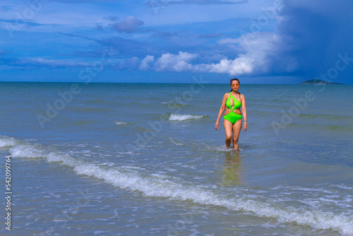Woman with swimsuit walking happy in the rain at beach