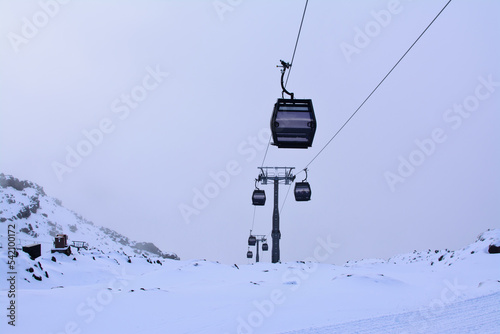 Cable cars going up and down snow blanketed slopes of the mountain while a snow storm building up. Mt Ruapehu, Whakapapa Sky Field, New Zealand