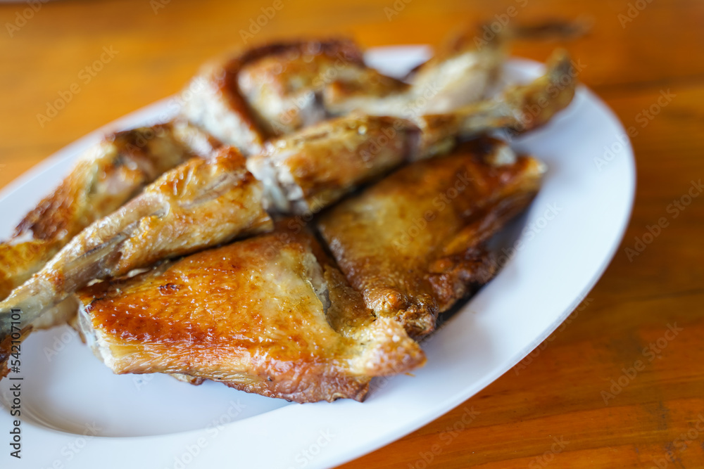 Grilled chicken in white plate on wooden floor - traditional Thai menu It's a simple and popular dish. Grilled chicken in white plate on wooden floor - traditional Thai menu It's a simple and popular dish.