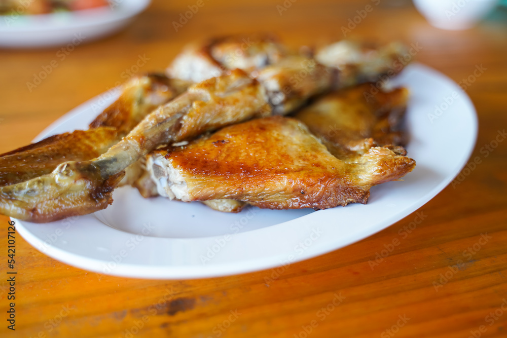 Grilled chicken in white plate on wooden floor - traditional Thai menu  It's a simple and popular dish.