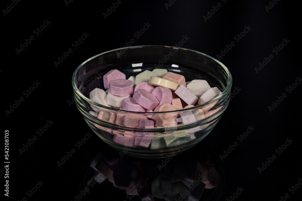 Fruit-flavored powder pastilles, powder lozenges in many colors and flavors, poured into a glass bowl on a black background, candies and sweets with a high sugar content Fruit-flavored powder pastilles, powder lozenges in many colors and flavors, poured into a glass bowl on a black background, candies and sweets with a high sugar content