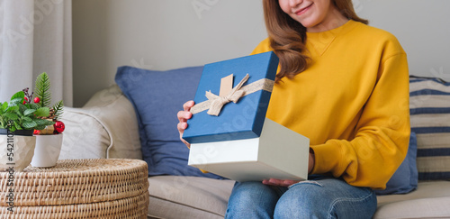 Bilde på lerret Closeup image of a young woman receiving and opening a gift box at home