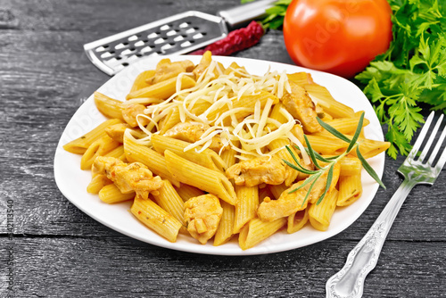 Penne with chicken and tomato in plate on board