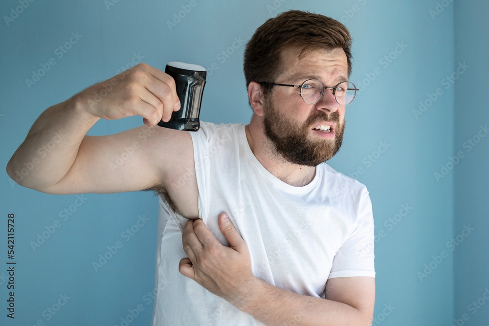 Irritated man sweats a lot and use an antiperspirant to prevent the