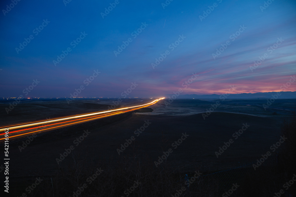 Streaming lights on highway at night. Long exposure of highway traffic under a blue and purple sunset.