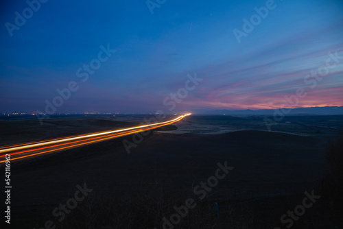 Streaming lights on highway at night. Long exposure of highway traffic under a blue and purple sunset.