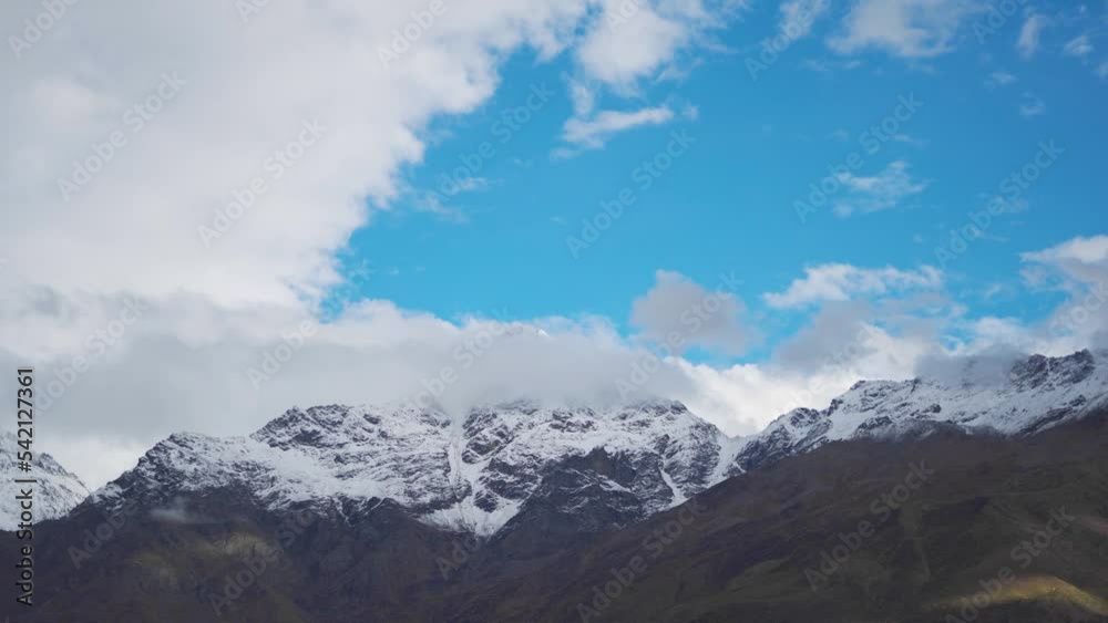 4K shot of clouds above the snow covered Himalayan mountain peaks as seen from Keylong in Lahaul Spiti, Himachal Pradesh, India. Clouds above the snowy mountain peaks. Natural background of winter. 4K shot of clouds above the snow covered Himalayan mountain peaks as seen from Keylong in Lahaul Spiti, Himachal Pradesh, India. Clouds above the snowy mountain peaks. Natural background of winter.