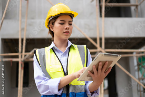 Woman Worker in a construction site. Female Architecture engineering holding a laptop on building site checking plans. Successful engineer or architect, Joyous businessman. Construction worker.