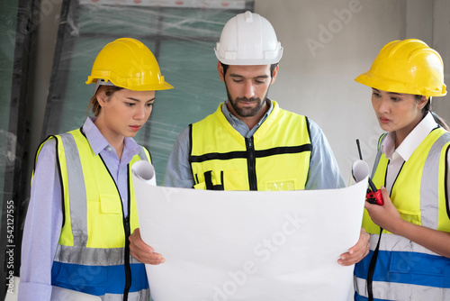 Engineers on building site. Engineer are working contruction on site plans to build high-rise buildings building. Architect caucasian man working with colleagues mixed race in the construction site.