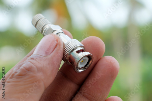 Male hand CCTV camera BNC plug connector. equipment for surveillance. photo