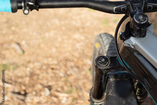 Personal prespective of a mountain bike: handlebar, front wheel and fork. 