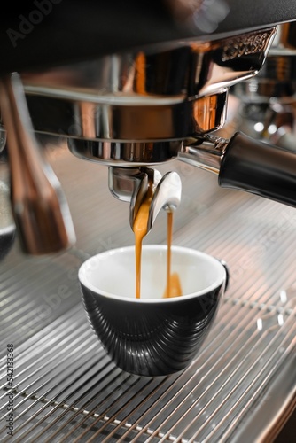 Vertical closeup of coffee pouring into a cup from the machine