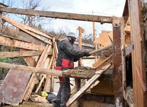 Workers disassemble and demolish an old wooden hut by hand