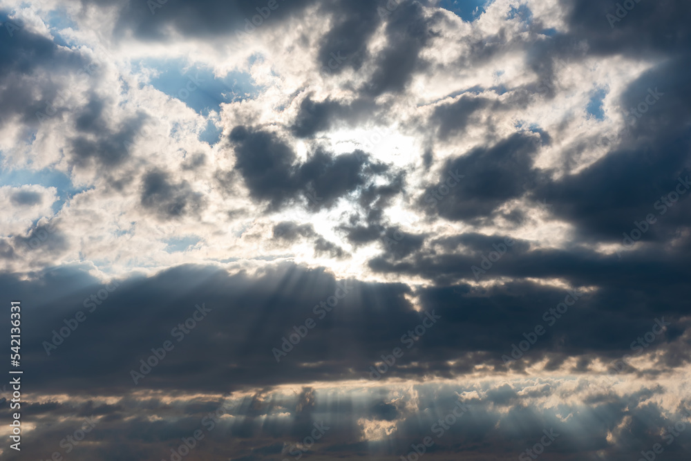 Sky background. Bright sunlight trough dark clouds. Copy space. Epic heaven