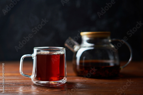 Teapot and cup of tea standing on a brown table